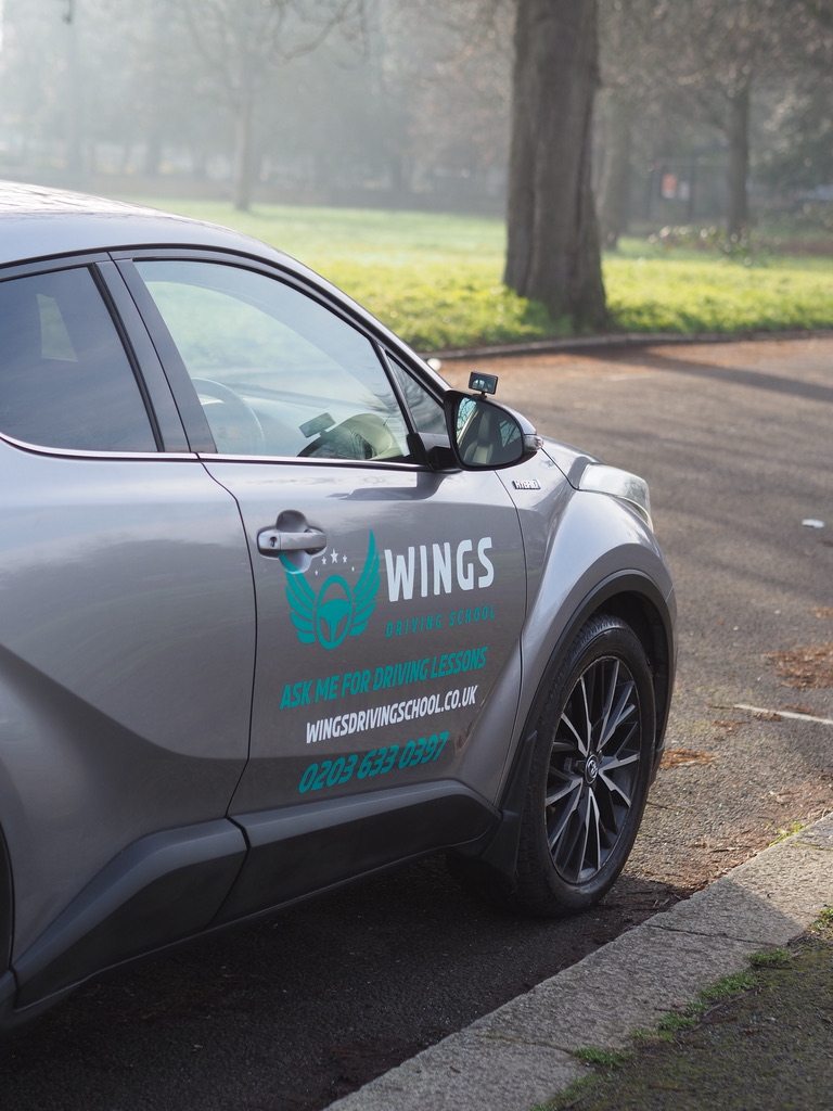 Wings Driving School car parked by a park